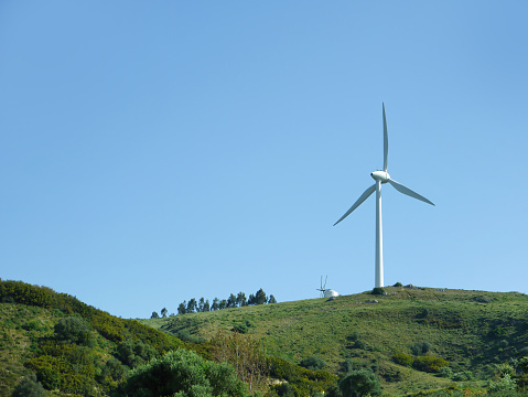 Sustainable eco power energy concept. Modern wind turbine on green hilltop, generating clean renewable and pollution-free energy farm, Windmill generator