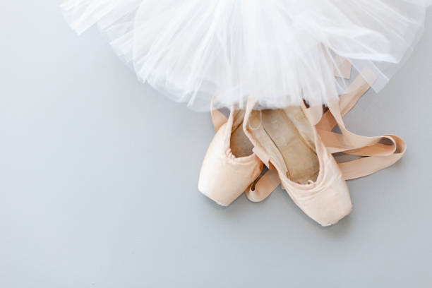 Ballet pointe shoes and white tutu skirt on gray background. Concept of dance, spring, ballet school, ballerina's clothes, stuff and things. Top view, flat lay. Copy space.
