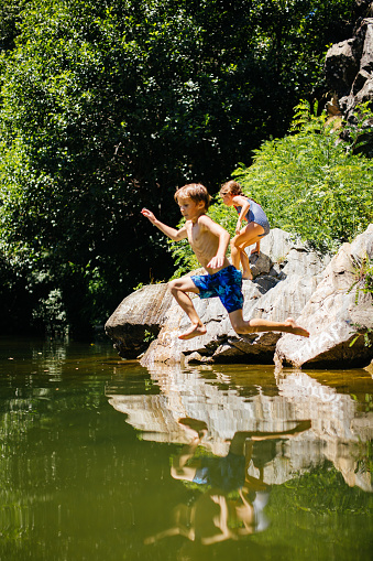 Children having fun on their summer vacation , jumping in the river