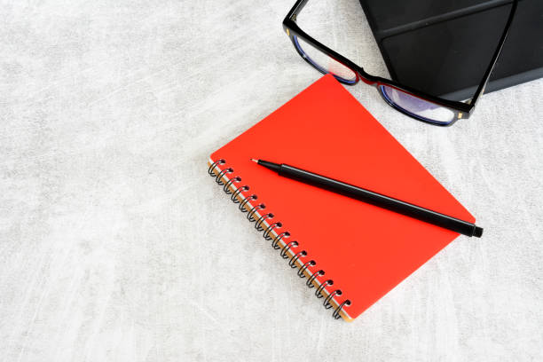 a red notebook with a black case and eyeglasses copy space