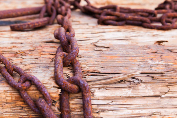 Rusty chains lie on wooden logs and hold them together close-up.