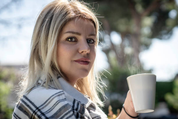 A woman in mittens holds a paper cup with a hot drink. A warming drink in winter.