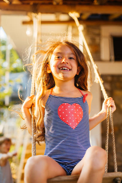 Cheerful child having fun swinging on a swing in the yard
