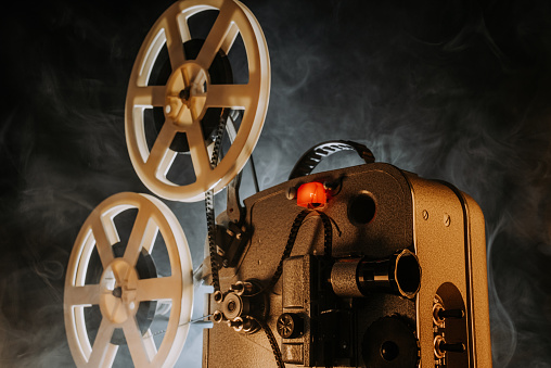 Retro projector playing motion picture in dark room. Timeless flicker of old films. Vintage objects, cinema, Hollywood concept. Perfect for festival background, broadcasting equipment. High quality