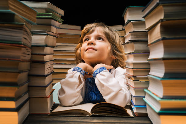 istock Dreamy ukrainian boy sitting at classroom or library desk. Smart child smiling 2110051139