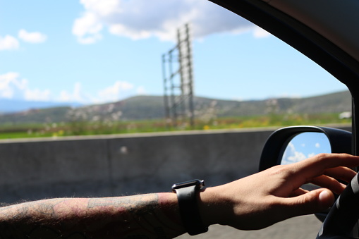 Ink on the Move: Tattooed Hands Steering Under Sunlight