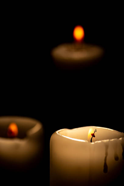Candles, beautiful candles positioned on dark surface, black background, selective focus.