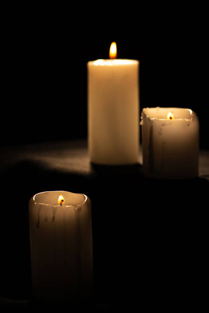 istock Candles, beautiful candles positioned on dark surface, black background, selective focus. 2110072407