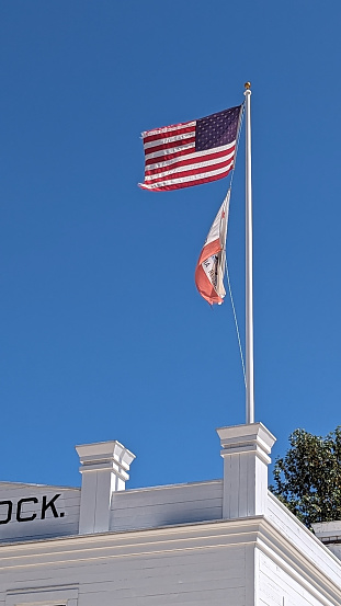 The United States Flab above the State flag of California atop an old-fashioned building