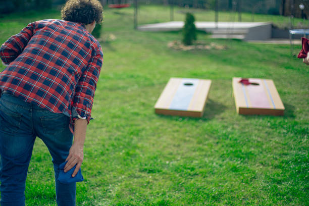 istock Backyard party, couple playing cornhole bean bag toss game 2110137856