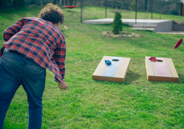 istock Backyard party, couple playing cornhole bean bag toss game 2110138902