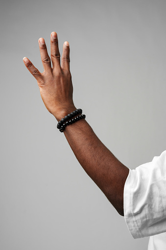 Human Hand Gesturing Four Fingers Up Against a Neutral Grey Background close up