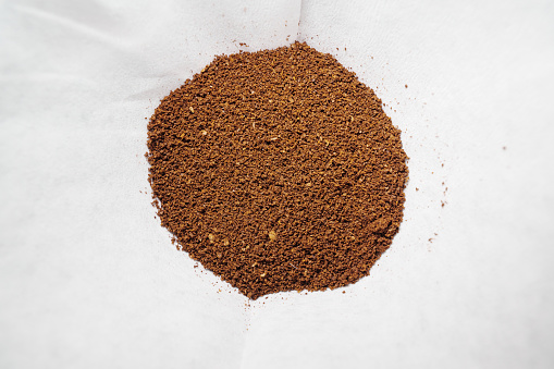 the focus is solely on the rich texture of ground coffee beans nestled within a pristine white coffee filter. The simplicity of the composition draws attention to the intricate details of the coffee grounds, highlighted against the clean backdrop of the filter