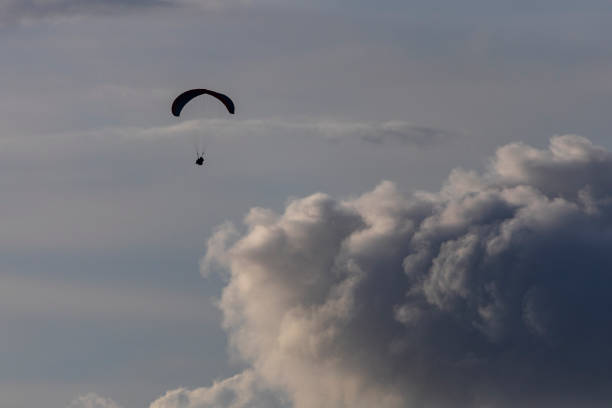 Parachutist moving quickly leaving clouds and blue sky behind
