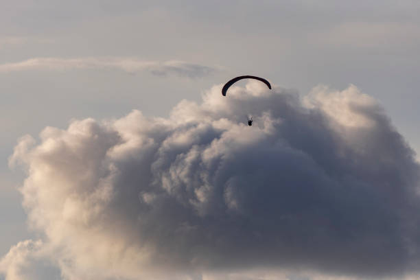 Parachutist moving quickly leaving clouds and blue sky behind