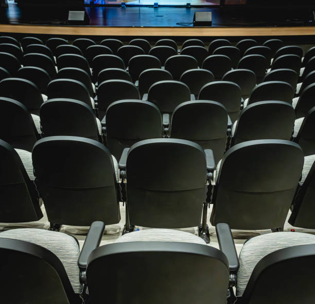 istock empty seats sit in an auditorium under a spotlight from the stage 2110204547