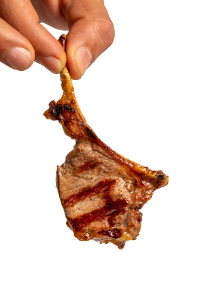 istock Freshly grilled lamb chops isolated on white background. He is holding a slice of cooked lamb chop in his hand. high quality photo. Close up 2110244800