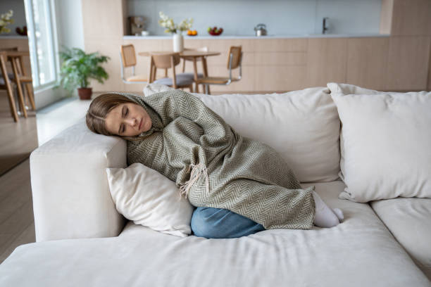 istock Unhealthy sad woman feeling cold covered with plaid lying on home sofa going through depression 2110275191