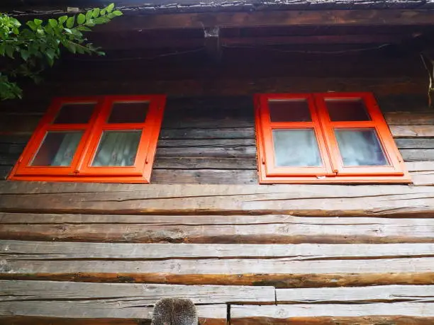 Ethno windows with a red wooden frame. Vintage house exterior. Architectural complex Stanisici. Log cabin. Izba building in rural wooded area on the territory of the settlement of the Eastern Slavs