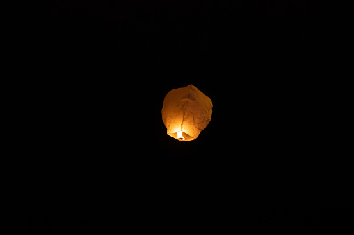 foreground, a single lantern in a completely black sky. powerful flame