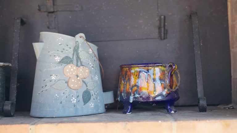 Old dusty crockery on brick shelf, painted porcelain bowls and copper jug, vintage crockery