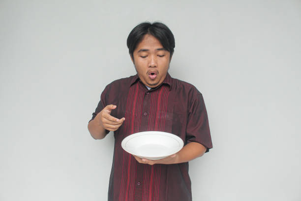 istock Young Asian man pointing to empty plate. 2110397312