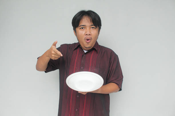istock Young Asian man pointing to empty plate. 2110398342