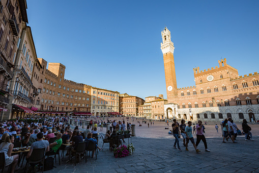 SIENA, ITALY - May, 2022: cityscape. View of famous Bell tower of the Palazzo Pubblico at the Piazzo del Campo at sunset time in Siena, Italy.