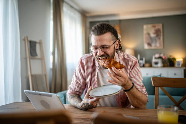 istock A young man eats croissants for breakfast at home 2110419636