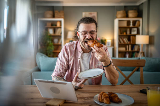 istock A young man eats croissants for breakfast at home 2110419640