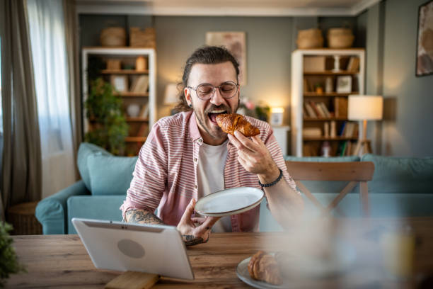 istock A young man eats croissants for breakfast at home 2110419642