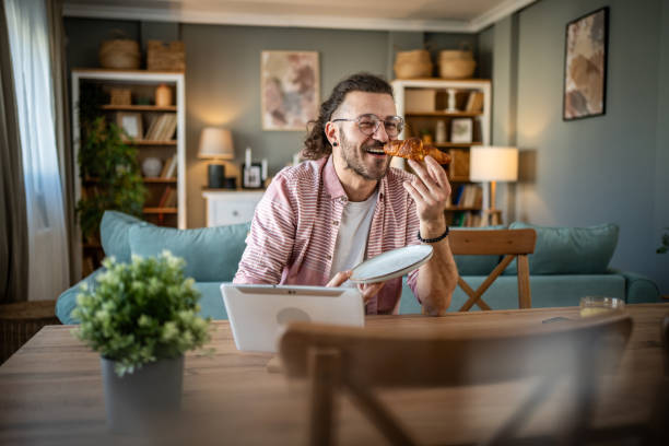 istock A young man eats croissants for breakfast at home 2110419651