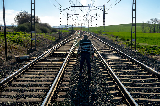 Middle-aged man in a rural area, uneven crossing of a train track, walking along the train track, Burgos - Spain