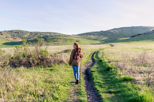 Woman with walking stick and hut while hiking