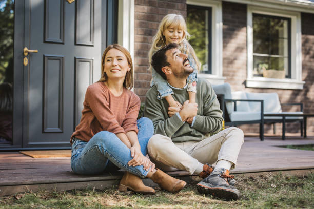Young family enjoying in sunny day Young family with little girl having fun in front of there house. Porch is decorated with flowers. home ownership stock pictures, royalty-free photos & images