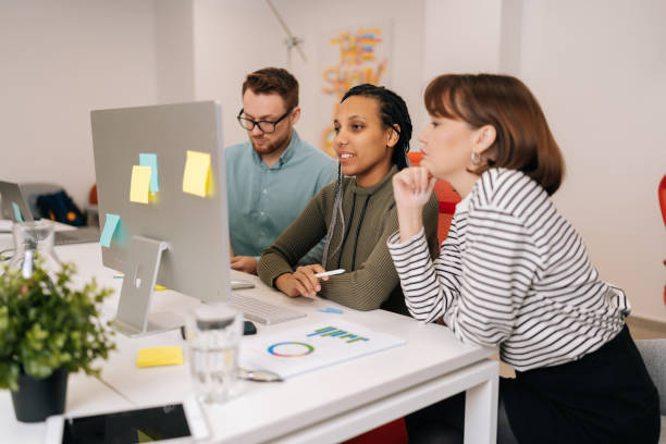 istock Portrait of multiethnic startup business team brainstorming using computer at workplace. African and Caucasian coworkers group discussing corporate project software 2110618588