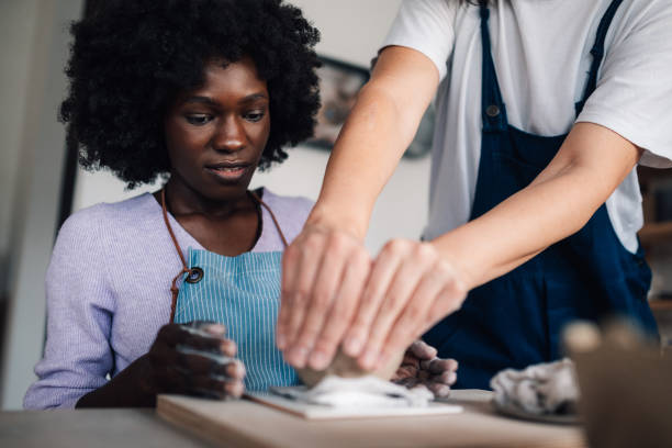 istock Interracial pottery course student making pottery with a help of tutor 2110624517