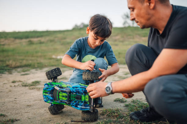 istock Son learning to fix his toy race car with father in nature. 2110624526