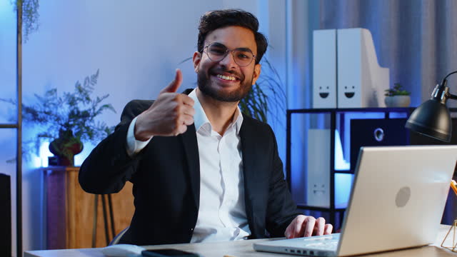 Happy business man looking approvingly at camera showing thumbs up, like positive sign, good news