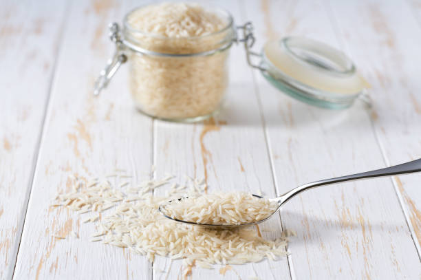 istock metal spoon with long rice basmati on a white wooden table. 2110645232