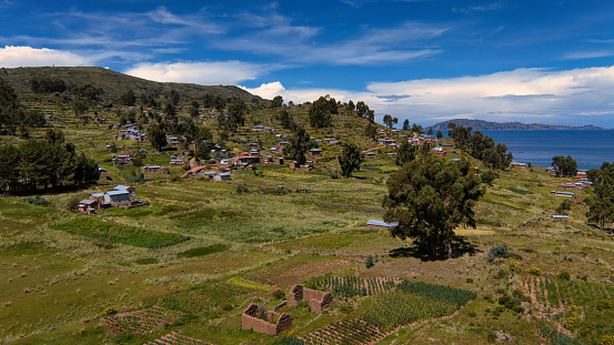 View over a village on the Capachica Peninsula on Lake Titicaca in Peru. Beautiful landscape, lake, mountains, fields, villages.