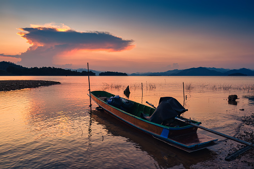 Colorful sunset view of the Kaeng Krachan reservoir with fishing boat and tourist rowing canoe at Phetchaburi, Thailand