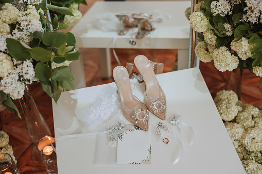 Details of the bride. Beauty is in the details. High-heeled bridal shoes. Gold wedding ring with a diamond. Perfumes. Earrings Wedding in details.