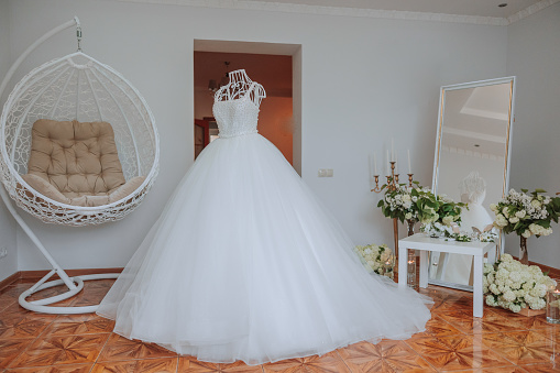 Bedroom interior with wedding dress prepared for the ceremony. A beautiful lush wedding dress on a mannequin in a hotel room.