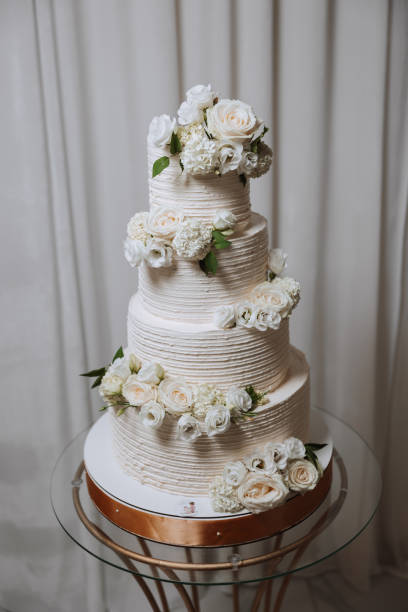 istock A large luxurious multi-tiered wedding cake is decorated with fresh white rose flowers in the banquet hall. Wedding dessert under the evening light. Wedding decor. 2110773227