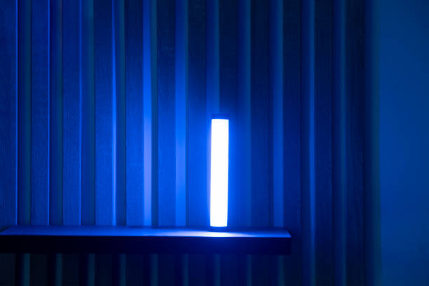 A single blue light stick emits a neon glow, creating a tranquil atmosphere in a dimly lit room with vertical blinds.