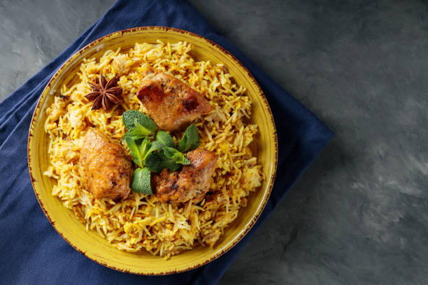 istock Plate of Chicken Biryani with Spices, Fresh Mint and Lemon on Dark Background, Copy Space 2110918465