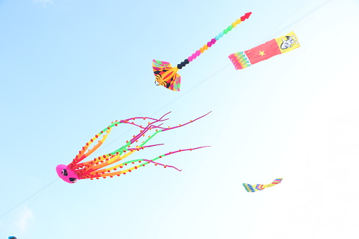 Colorful kites flying in the clear blue sky background - popular outdoor toys at Mekong Delta Vietnam. Happy childhood moments.
