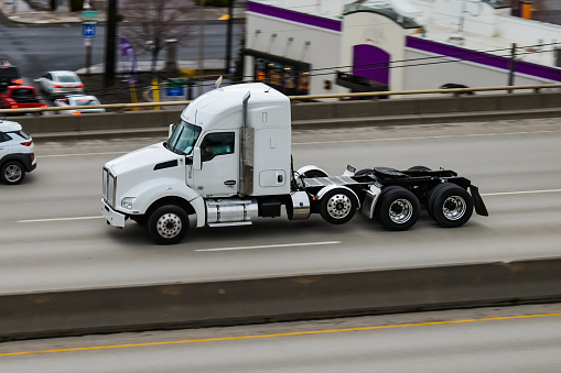 A semi tractor driving down the freeway without a trailer.