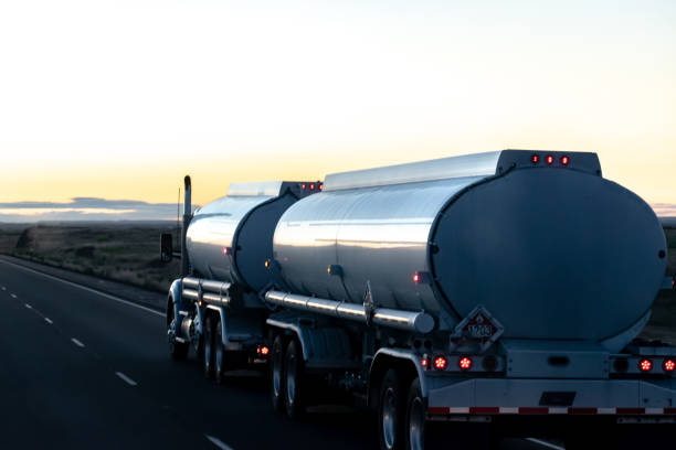 A fuel tanker driving on the freeway at dawn.